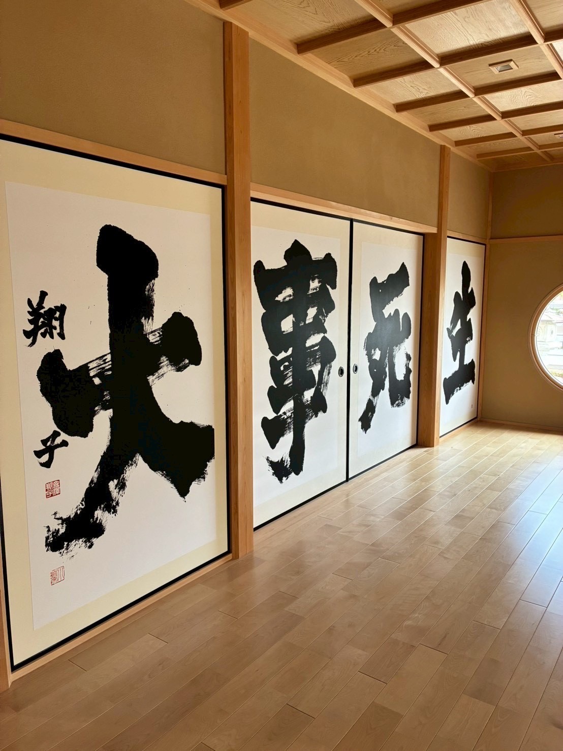 洗練された格天井と力強い襖書、情緒ある丸窓が調和する廊下